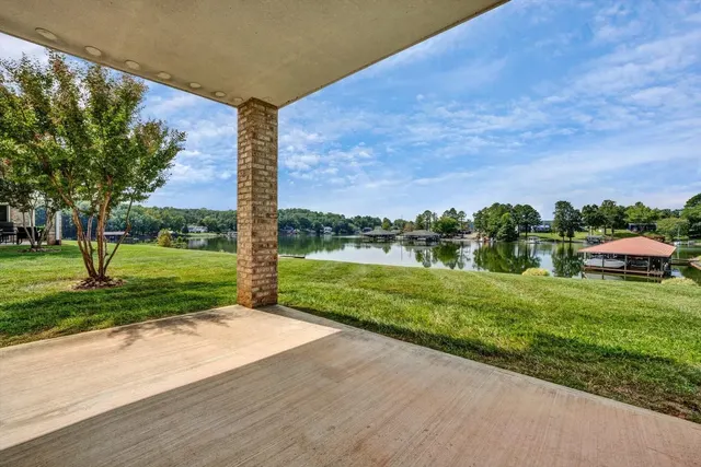 Covered lower-level patio opening onto lawn with the lake in the distance
